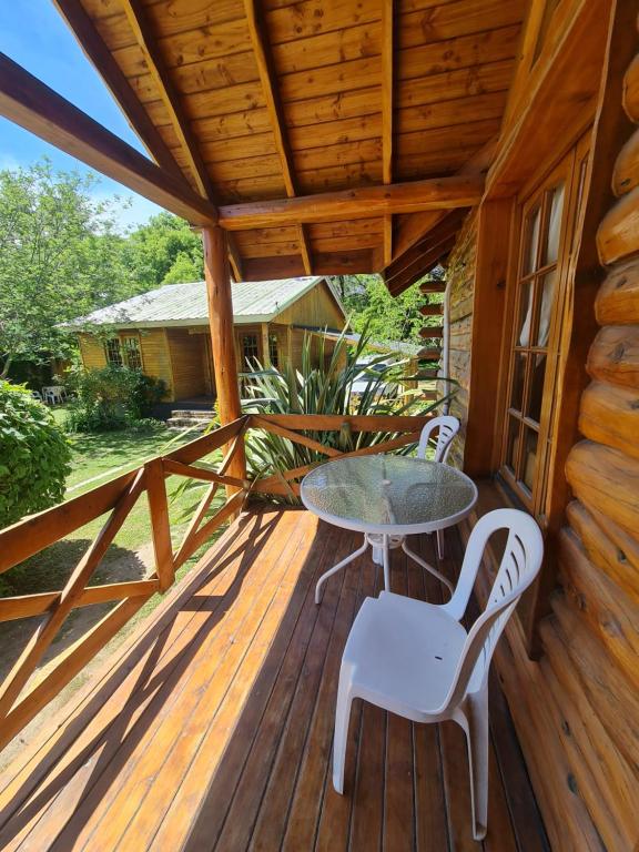 Galería con mesa y reposeras de una cabaña de La Ponderosa