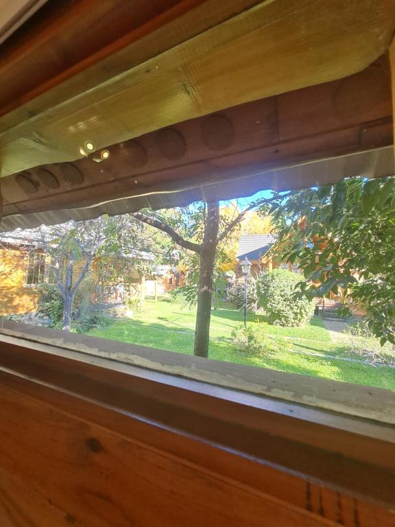 Vista al jardín verde desde la ventana de una cabaña